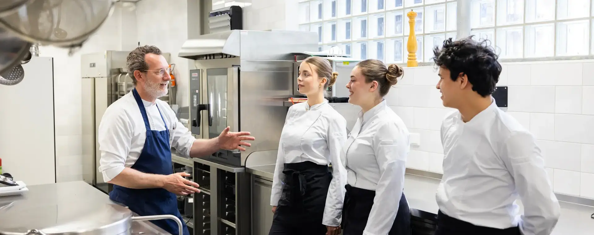  Studenten krijgen uitleg van een kok tijdens de praktijkles