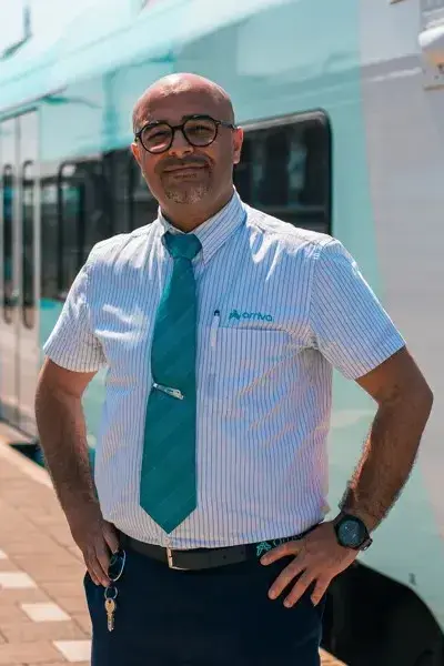 Treinmedewerker op perron poseert voor trein