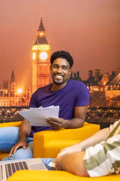 Twee zittende studenten voor een Londen-achtergrond