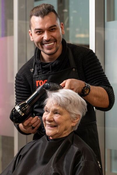 Student Haarverzorging föhnt haar oudere dame in kapsalon