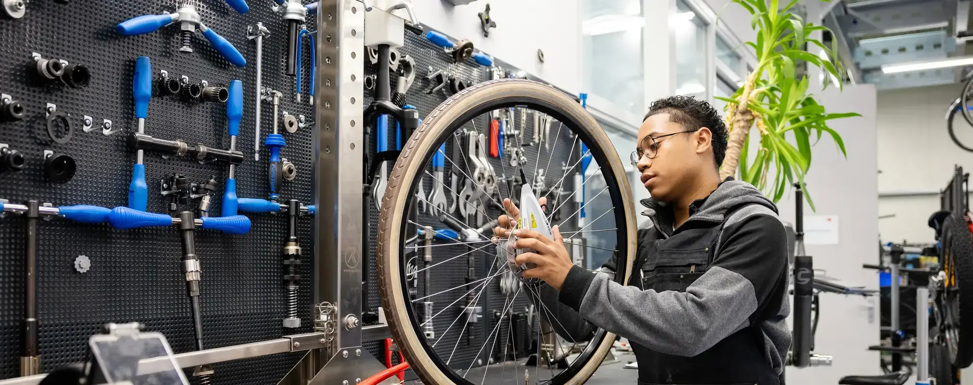 Student sleutelt aan fietswiel in werkplaats