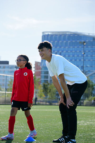 Student coacht meisje in trainingspak op sportveld
