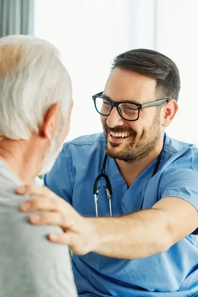 Dokter met stethoscoop ondersteunt en glimlacht naar patiënt.
