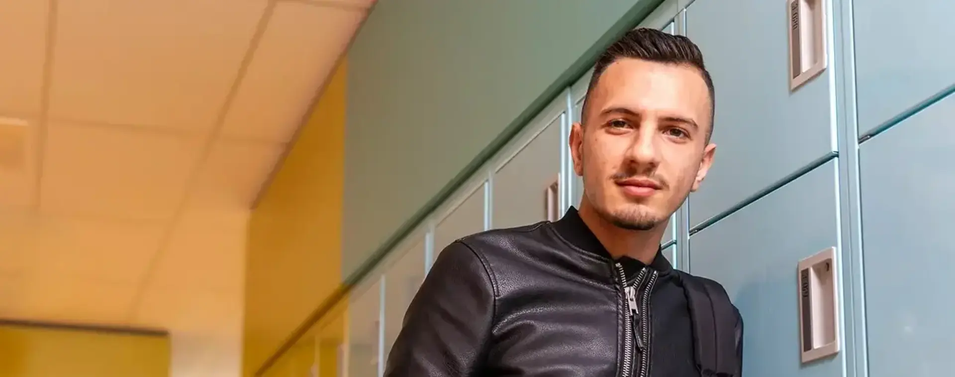 Student in leren jack poseert voor kluisjes op school