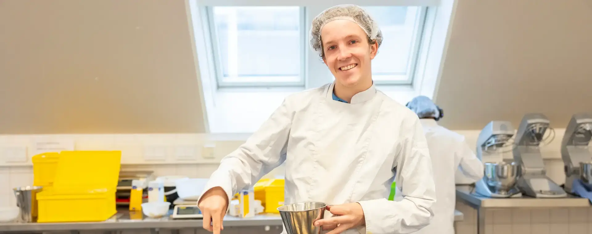 Student Bakker smeert broodjes in op bakplaat in praktijklokaal