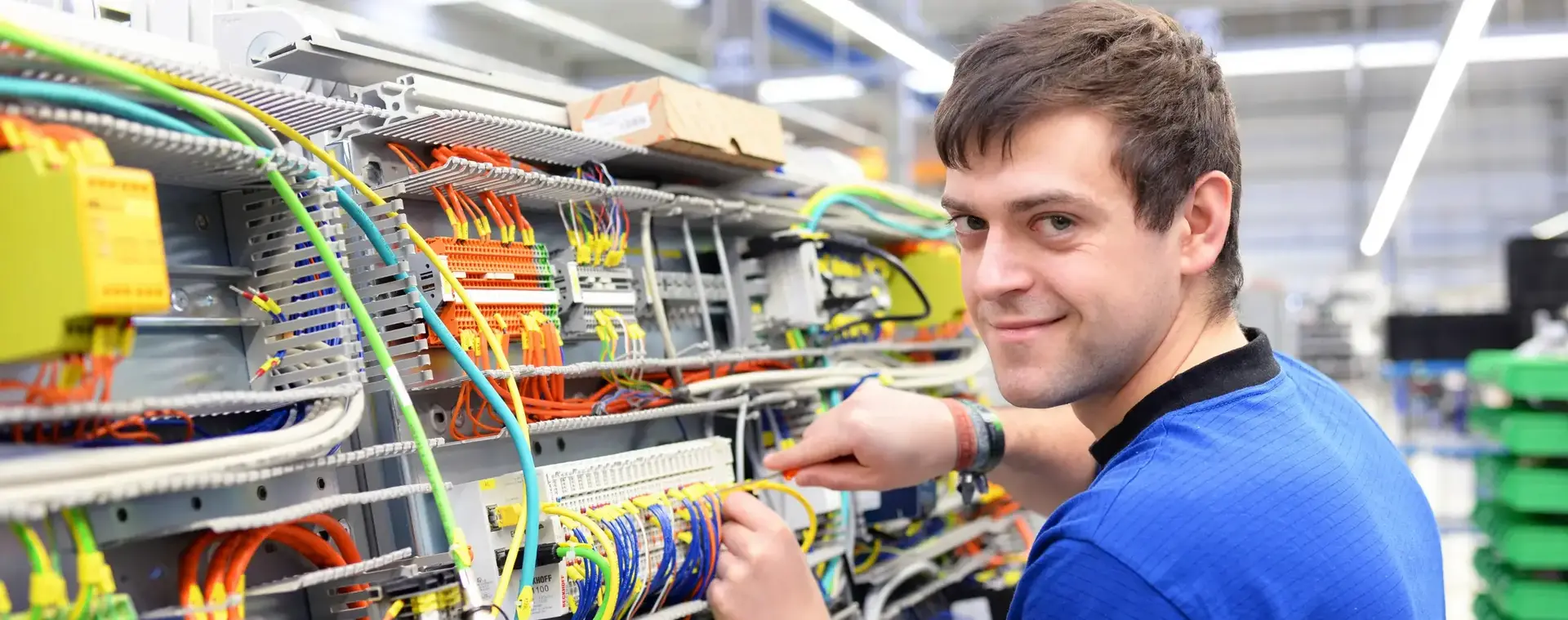 Man sleutelt aan elektrotechnische installatie en lacht in camera