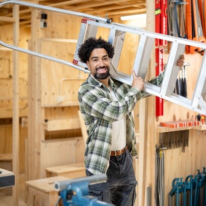 Student Bouw draagt ladder op zijn schouder in werkplaats