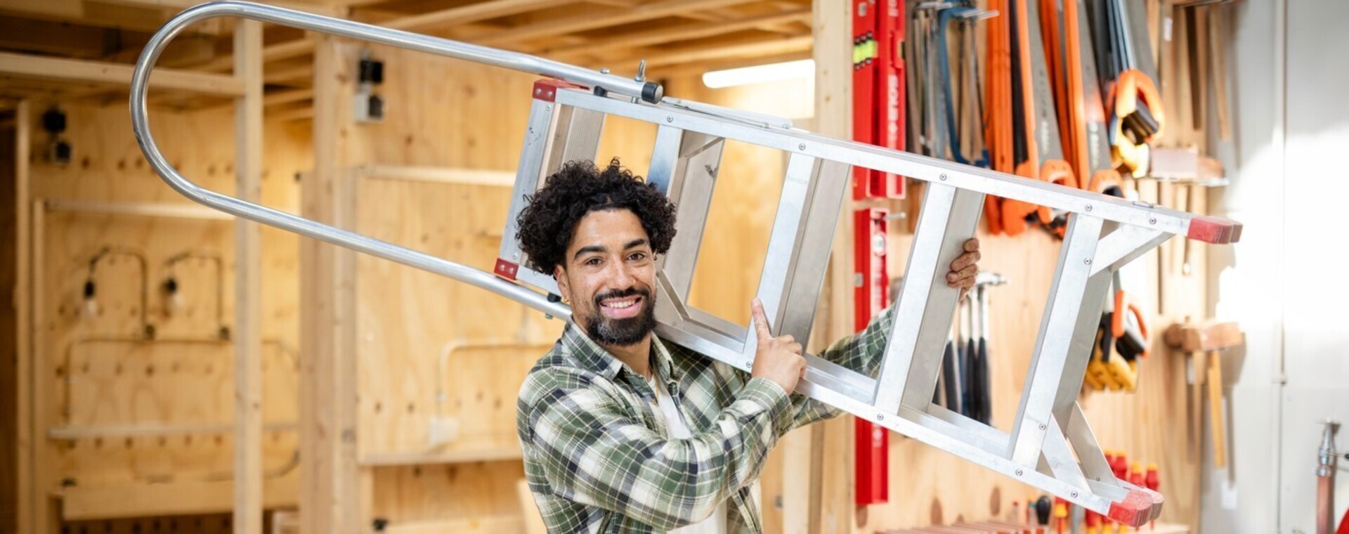 Student Bouw draagt ladder op zijn schouder in werkplaats