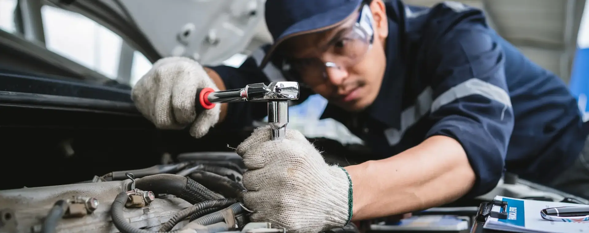 Student repareert onderdeel van automotor in werkplaats