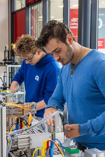 Studenten werken aan een technische installatie tijdens de praktijkles.