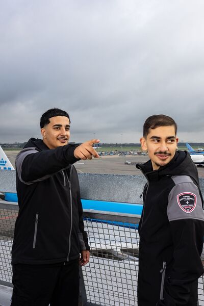 Studenten Luchthavenbeveiliger op Schiphol met KLM-vliegtuig op de achtergrond