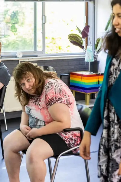 Jonge vrouw staat in een lokaal met zittende luisterende personen