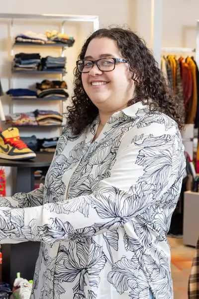 Student in hippe kledingzaak poseert met sneaker, met haar collega op de achtergrond