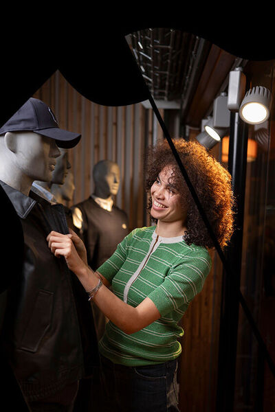 Verkoopster kleedt paspop aan in winkel