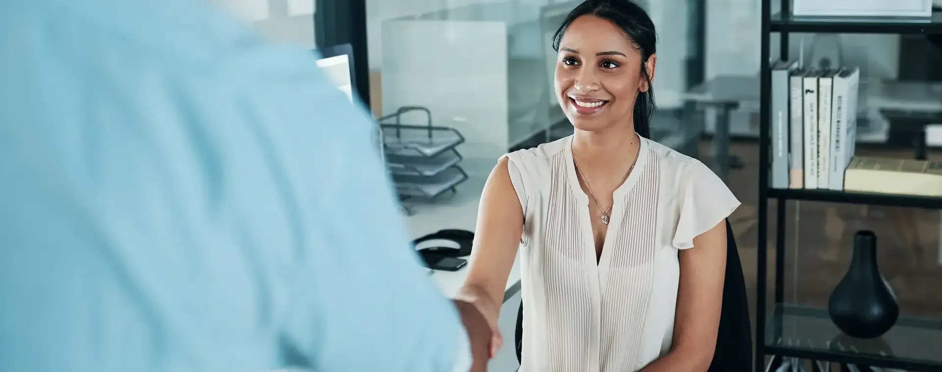 Student achter balie schudt de hand van een klant.
