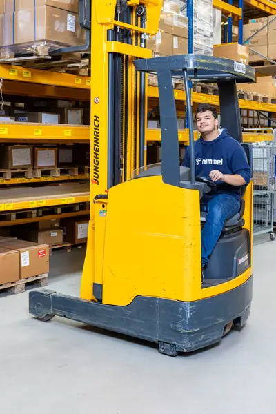 Logistiek medewerker bedient een gele reachtruck in een magazijn.