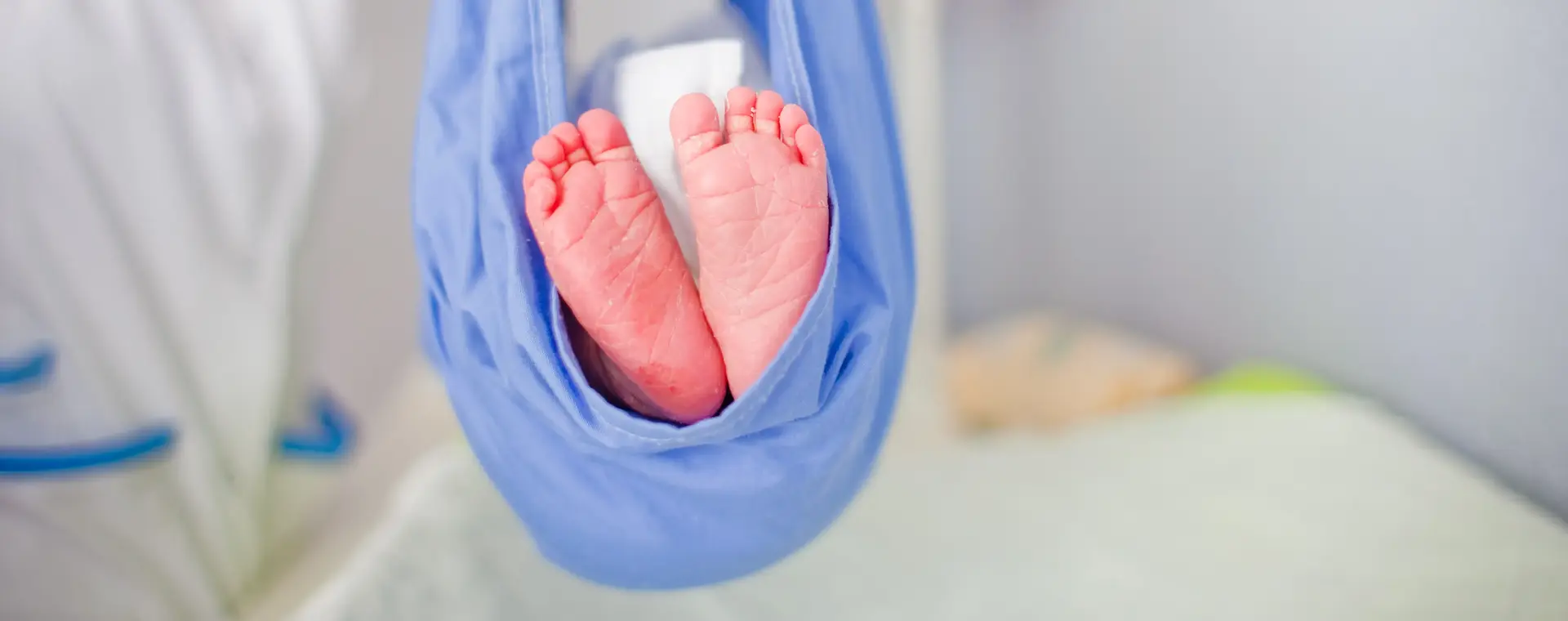 Kraamverzorgende houdt baby omhoog in doek