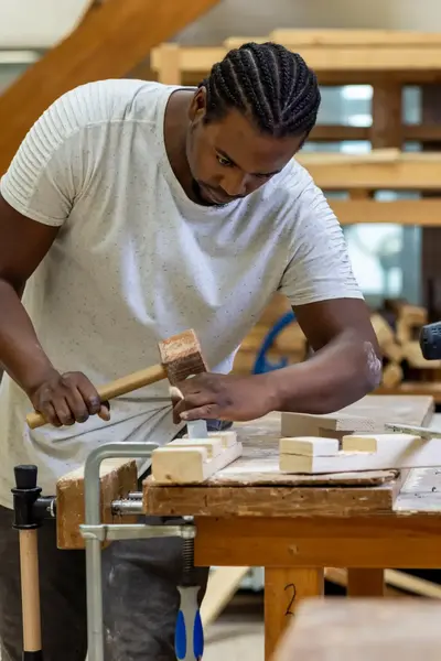 Jongeman timmert aan een stuk hout