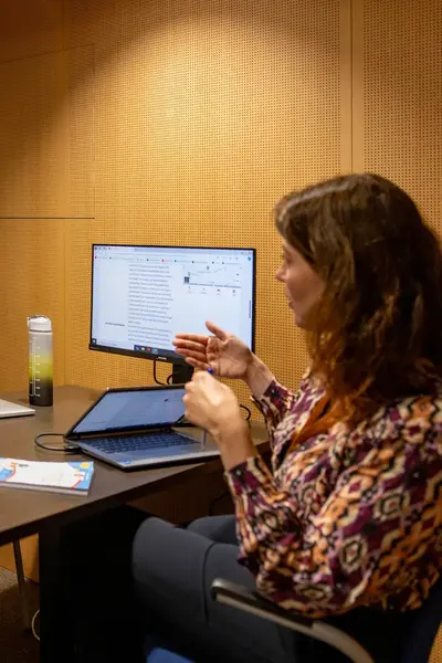 Drie vrouwen in overleg aan een tafel met laptops en notities.
