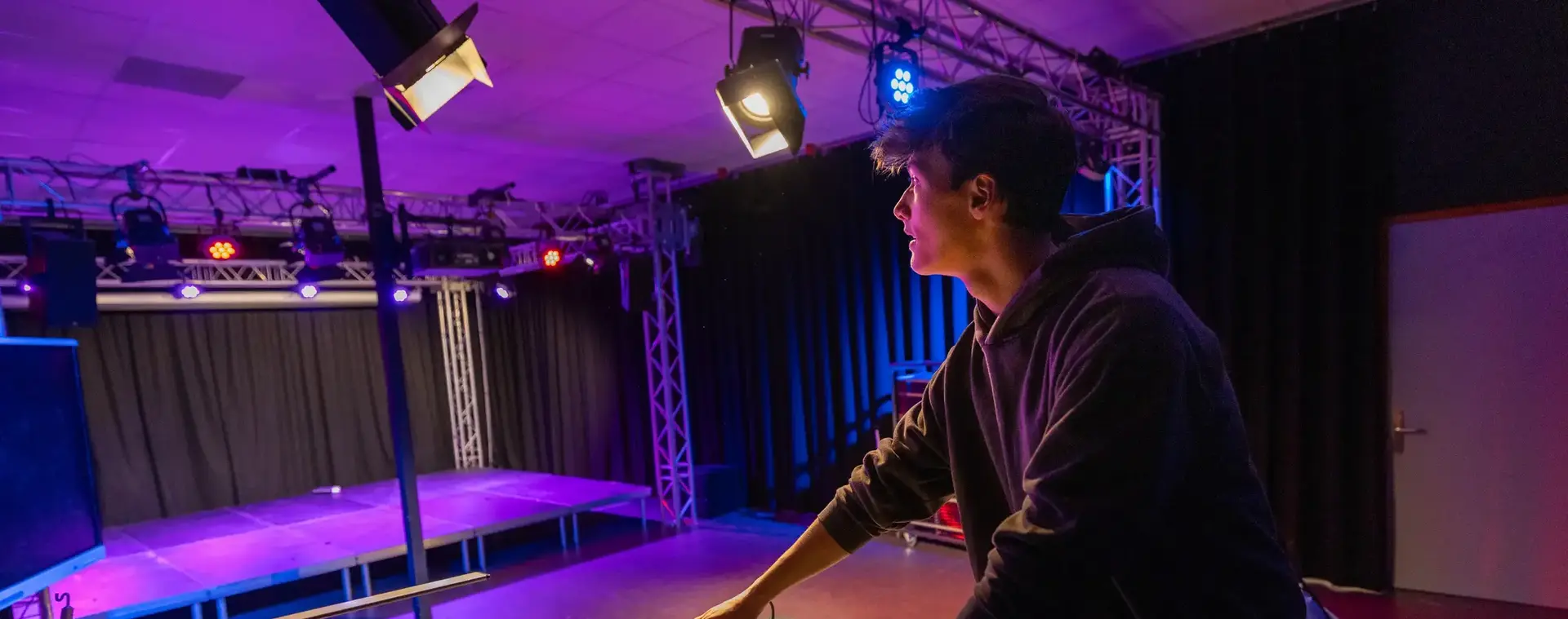 Student met regelt met lichtpaneel het licht op het podium.