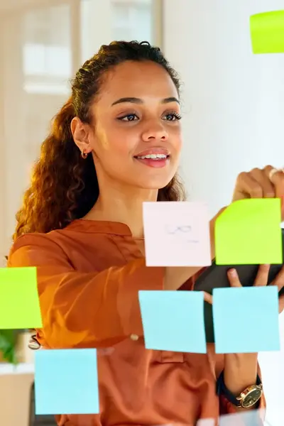 Studente plakt post-its op een glazen overzichtsboard.