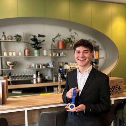 Student Guest Experience Manager Daan poseert met zijn gouden medaille in bar