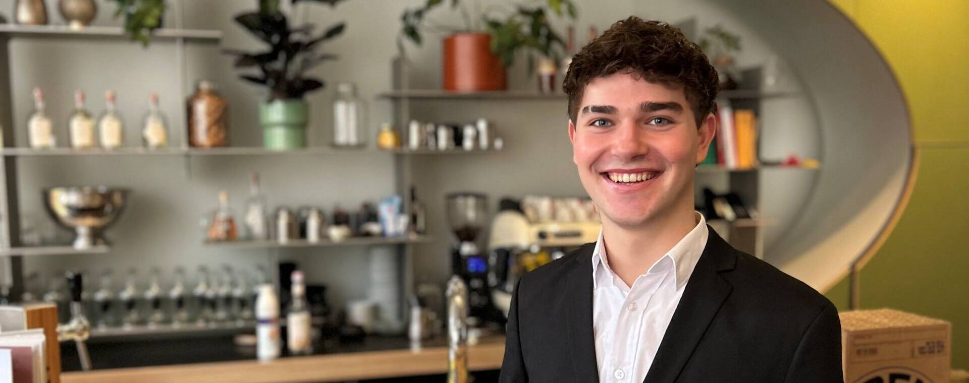 Student Guest Experience Manager Daan poseert met zijn gouden medaille in bar