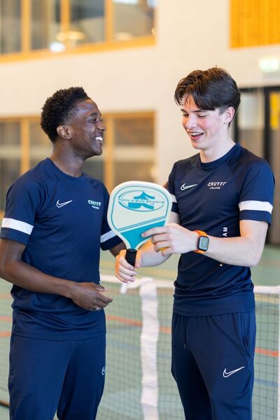 Twee studenten in sportkleding met bat in gymzaal