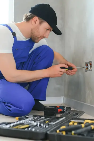 Student in werkkleding werkt aan een stopcontact in een woning