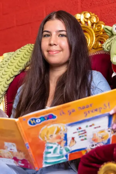 Jonge dame met boek en knuffels in voorleesstoel 
