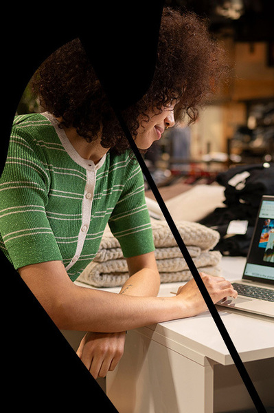 Verkoopster achter laptop in kledingwinkel