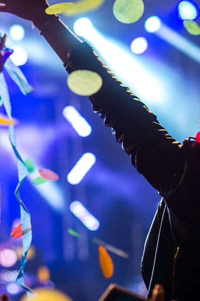 Confetti dwarrelt neer op jongeren die met hun handen in de lucht staan te feesten.