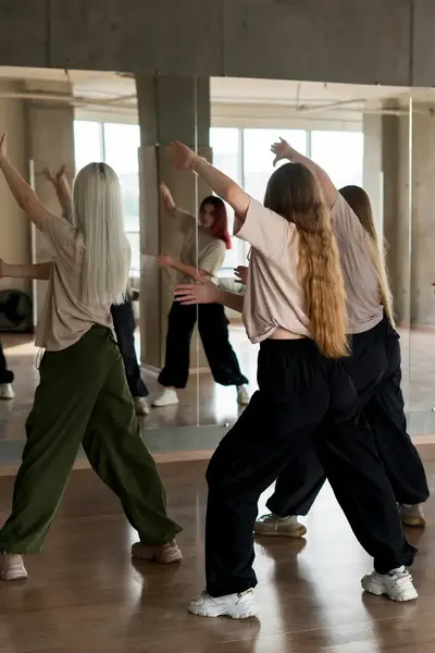 Studenten oefenen een dansroutine in een spiegelzaal.