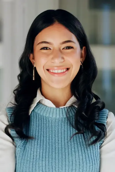Student met lange donkere krullen lacht naar de camera.