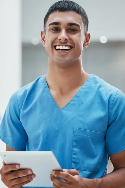 Verpleegkundige met tablet glimlacht in het ziekenhuis.