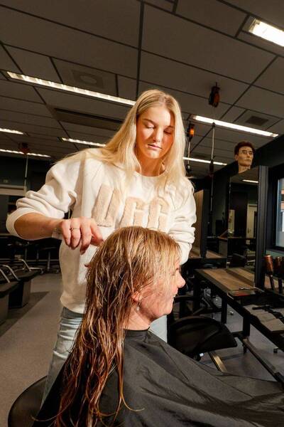 Student Haarverzorging knipt model in salonsetting
