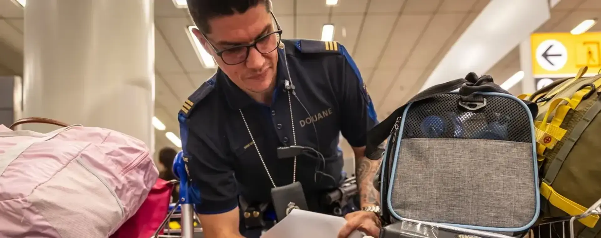 Douanier controleert labels op mandjes huisdieren op vliegveld