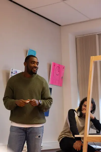 Een docent staat voor de klas bij een whiteboard met het woord 'Beroepshavo'. Hij spreekt de leerlingen aan, terwijl een student op de voorgrond aandachtig luistert.