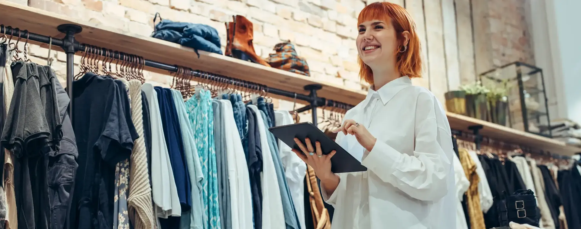 Kledingverkoopster met tablet in hand in winkel