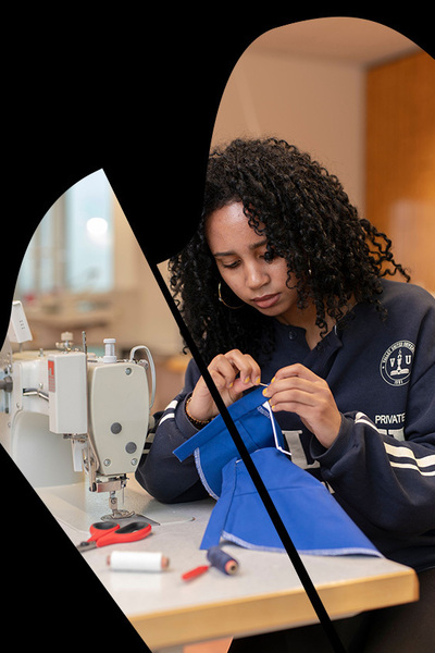 Student Fashion met naald en draad bezig achter naaimachine